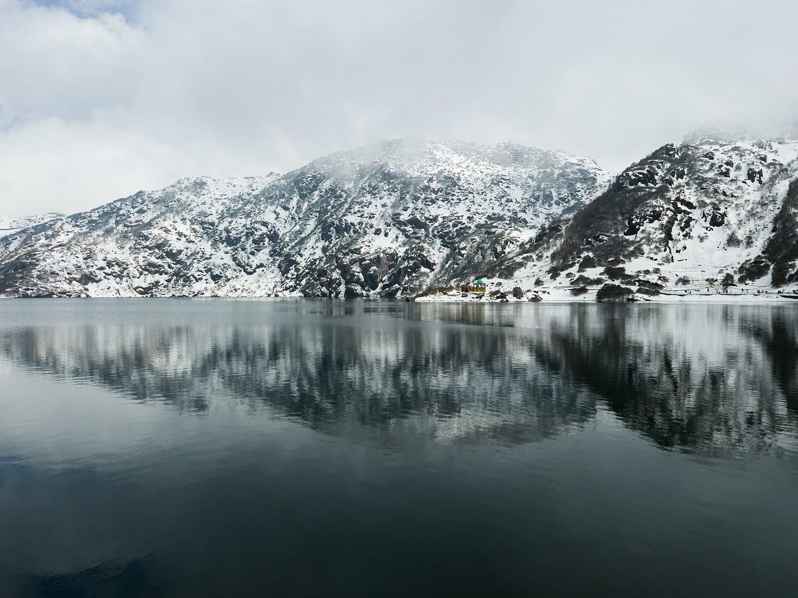 Snow-dusted mountains reflected in the still water of Tsomgo Lake